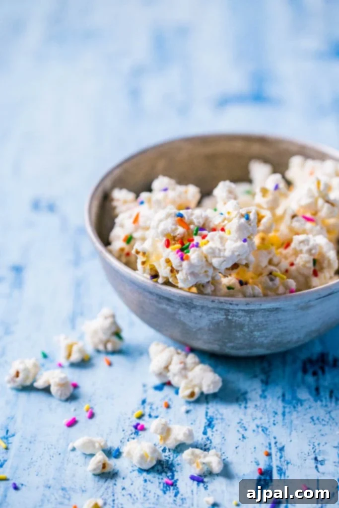 Birthday Cake Popcorn 9 A large bowl brimming with vibrant white chocolate cake batter popcorn and sprinkles.