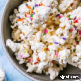 A bowl of cake batter popcorn with sprinkles in it.