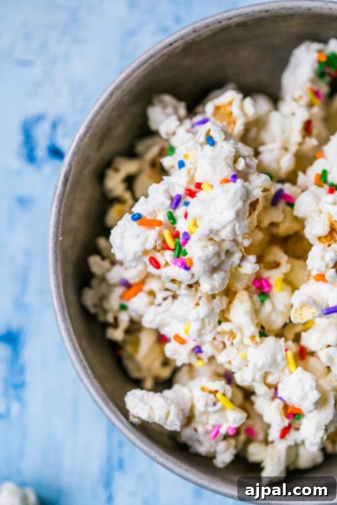Birthday Cake Popcorn 6 A close-up shot of individual pieces of white chocolate cake batter popcorn with colorful sprinkles.