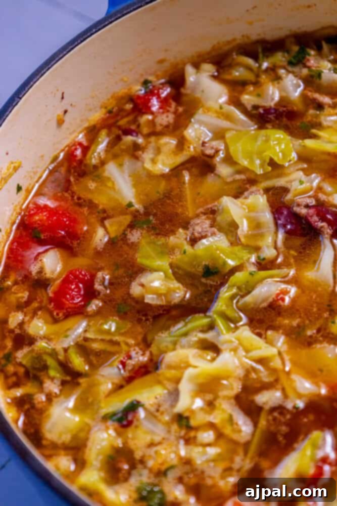 A simmering pot of hearty cabbage soup, brimming with ground beef and colorful vegetables.