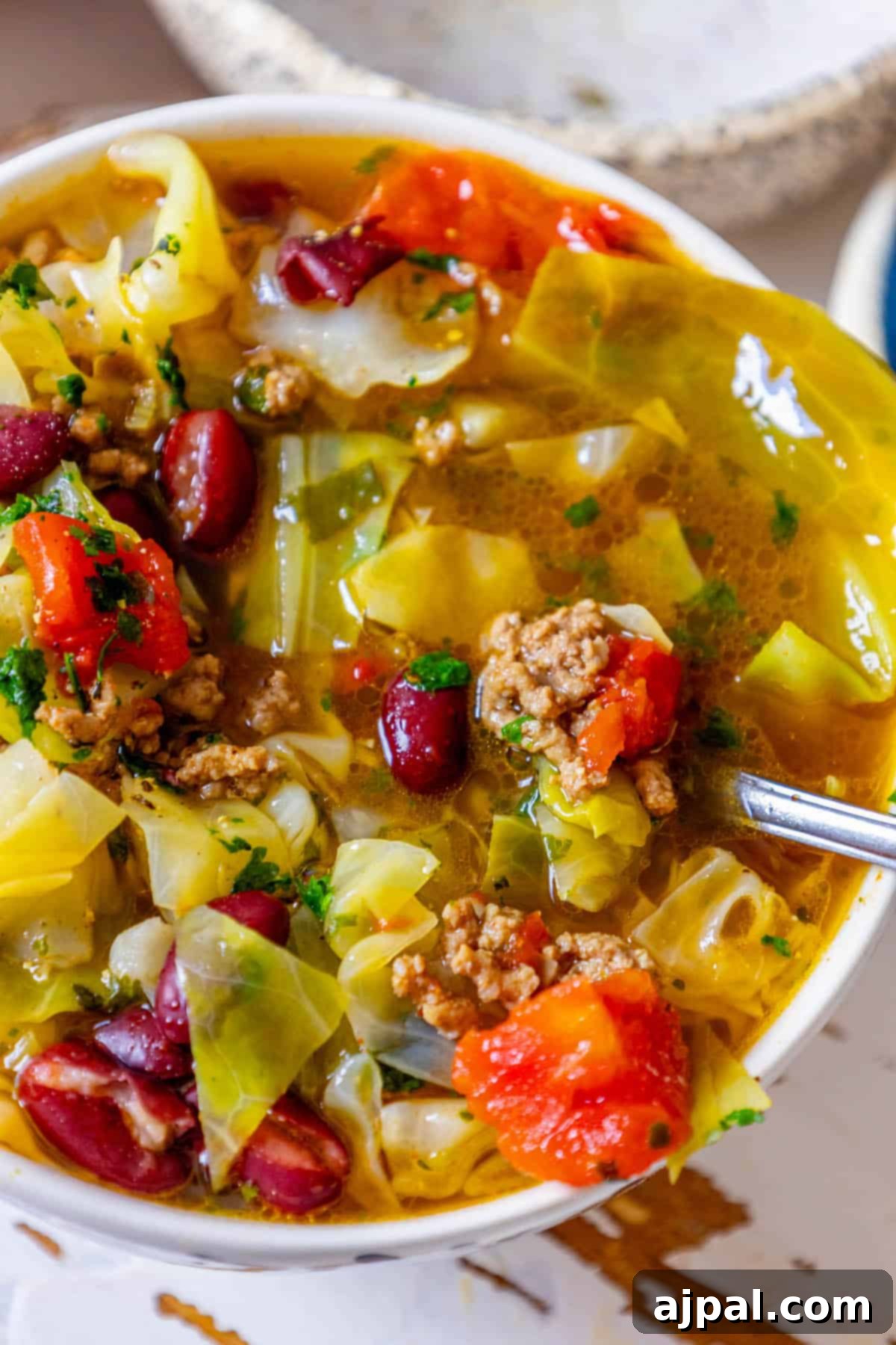 A close-up shot of hearty cabbage soup, with visible pieces of tender cabbage and savory meat, promising a comforting meal.