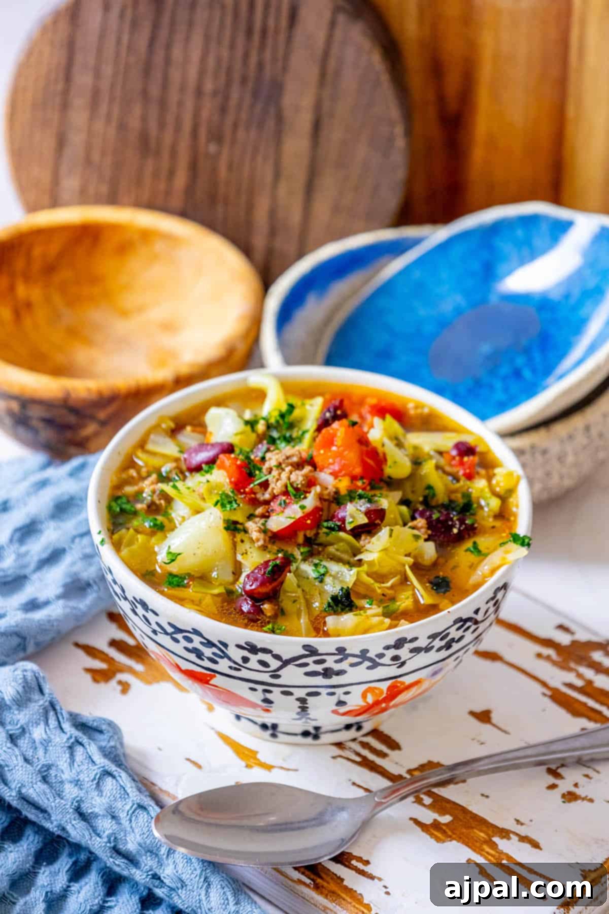 A bowl of rich cabbage soup with tender ground beef, served on a rustic wooden table.