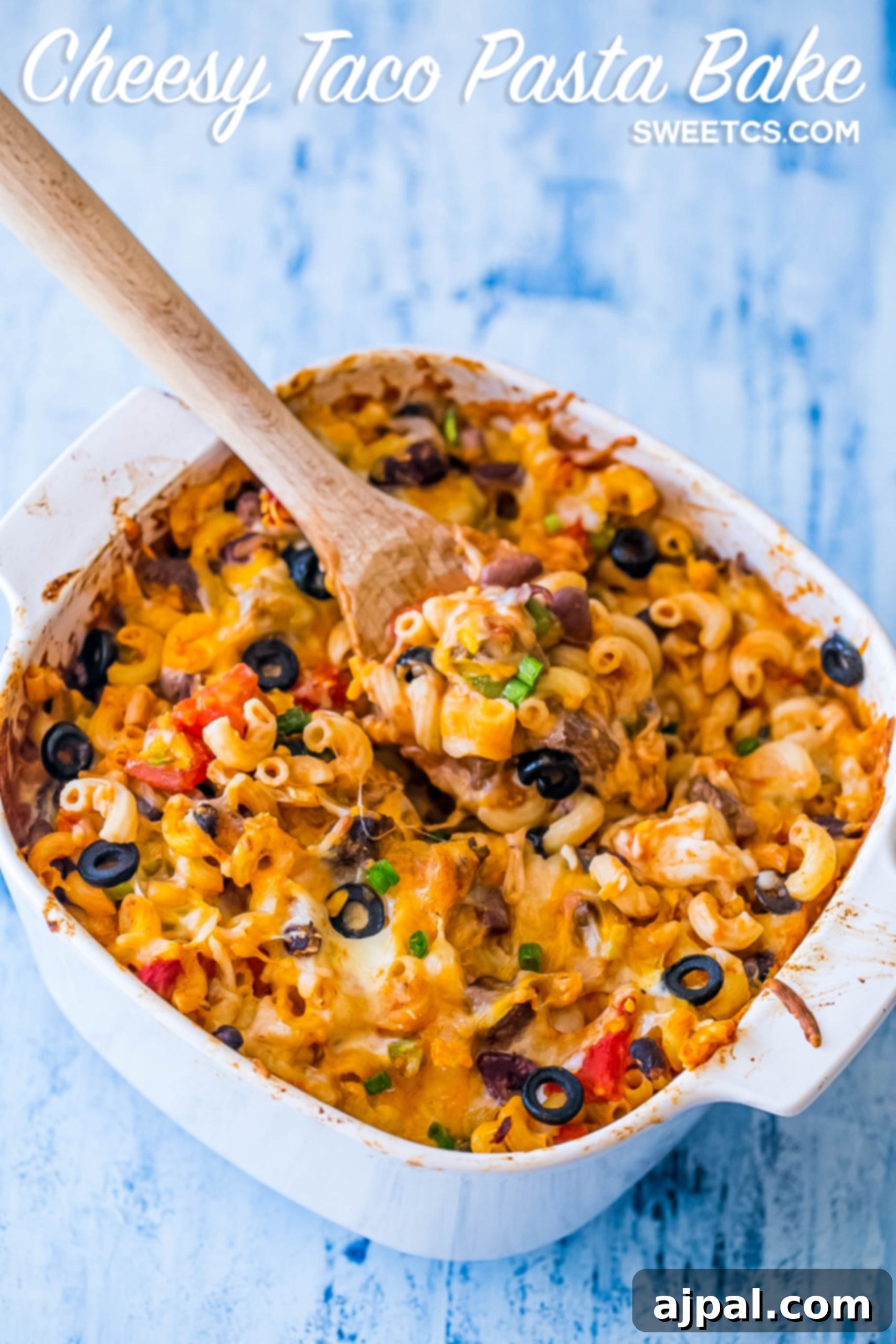 Ingredient shot for Cheesy Taco Pasta Bake, showing diced bell peppers, cheese, black beans, diced tomatoes, cooked pasta, and stew meat laid out on a kitchen counter.