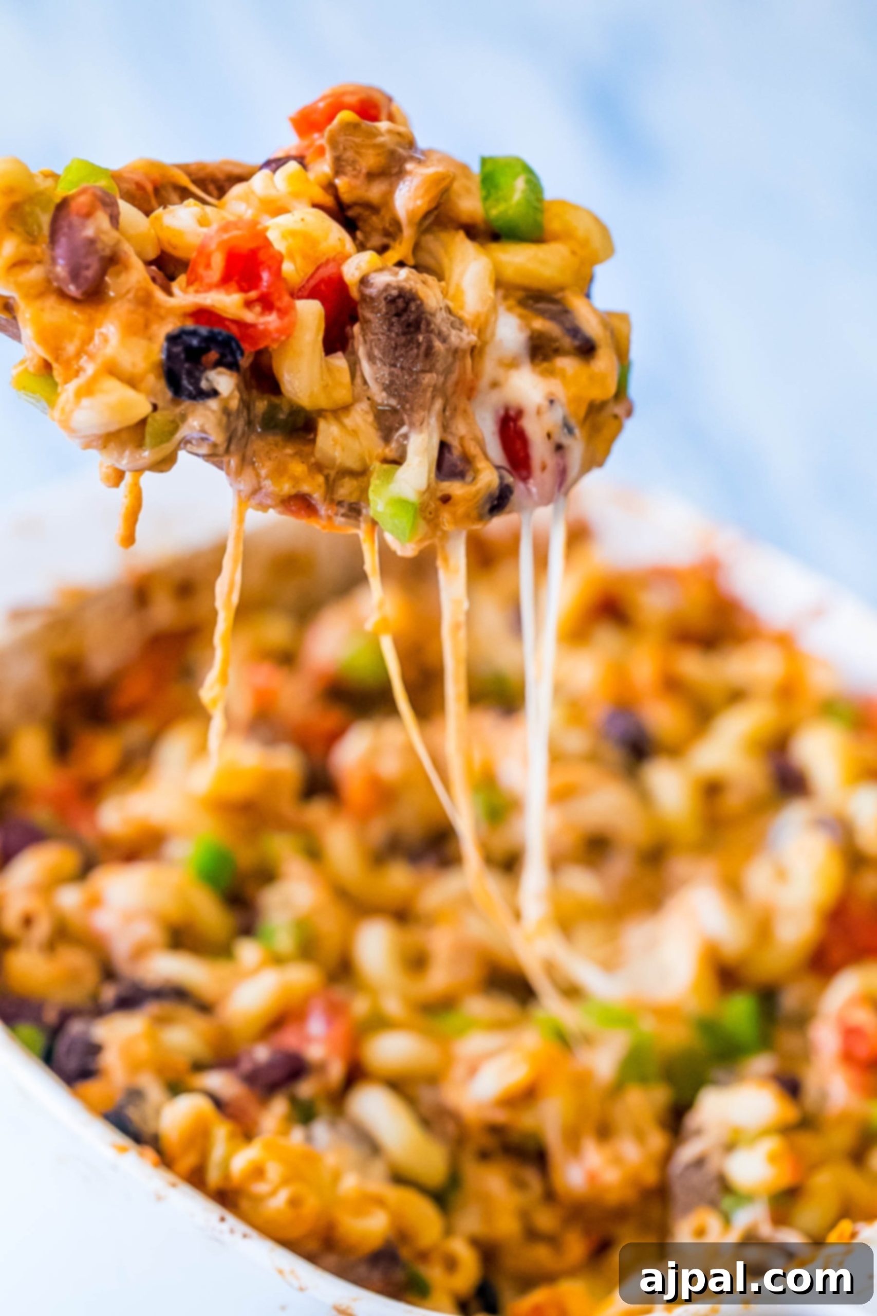 Overhead shot of a full Cheesy Taco Pasta Bake in a casserole dish, garnished with fresh cilantro and lime wedges, ready for serving.