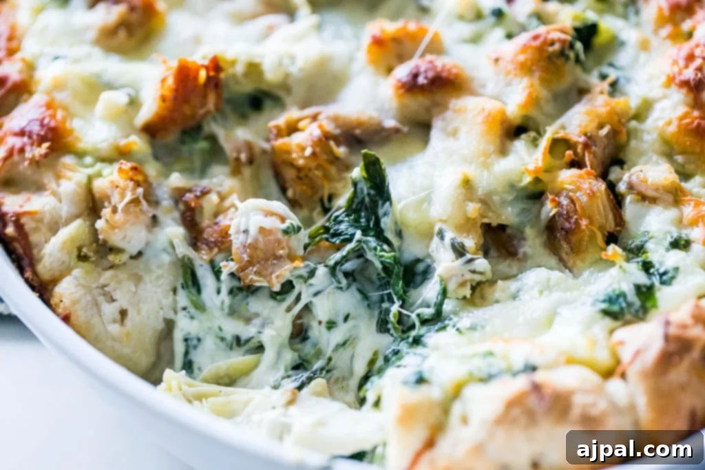 A detailed close-up shot of the cheesy chicken, spinach, and artichoke bread dip, showcasing its creamy texture and rich ingredients.