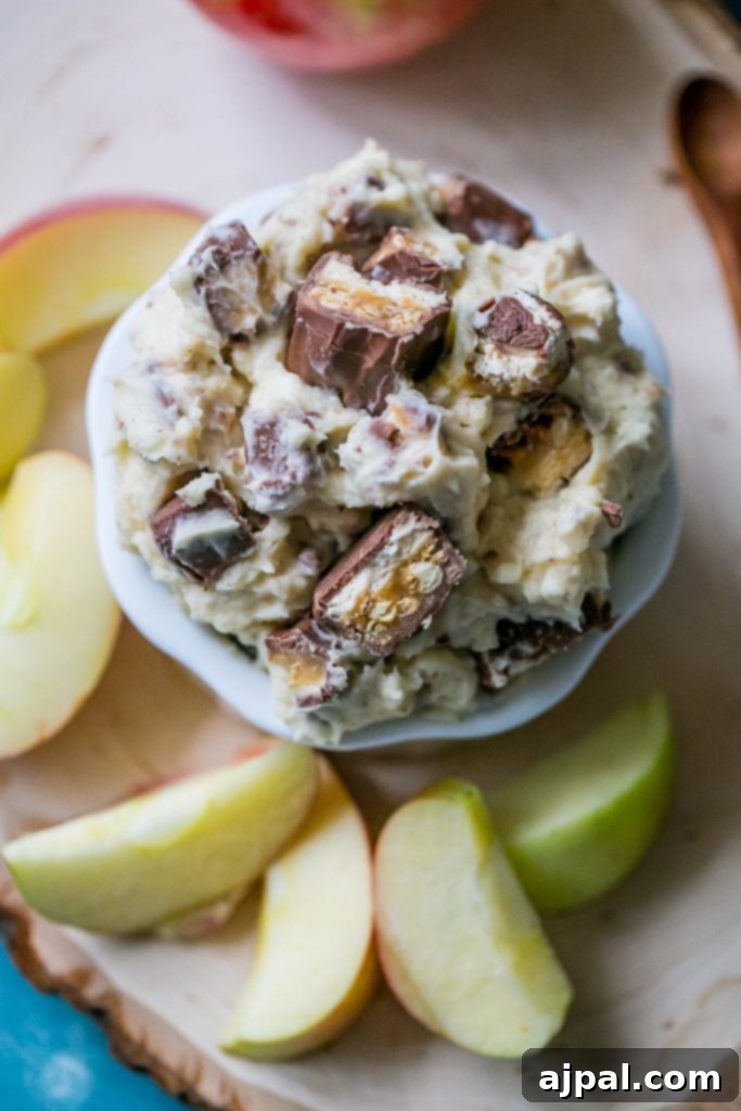 A bowl of Snickers fruit dip garnished with more chopped Snickers pieces, ready to be served.