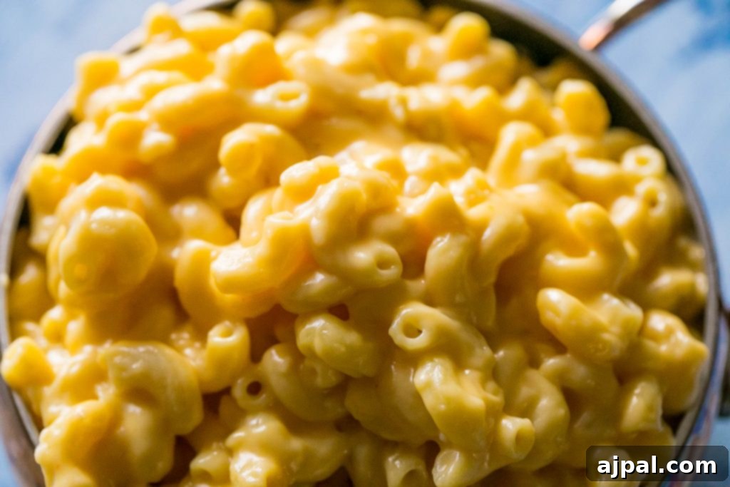A serving of mac and cheese in a rustic bowl, garnished with fresh herbs and black pepper.