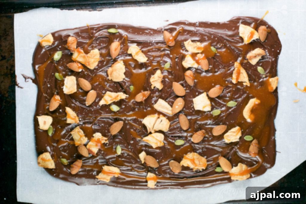 Decadent Caramel Apple Chocolate Bark 4 A large piece of homemade caramel apple chocolate bark, showing layers of chocolate, caramel, apples, and nuts.