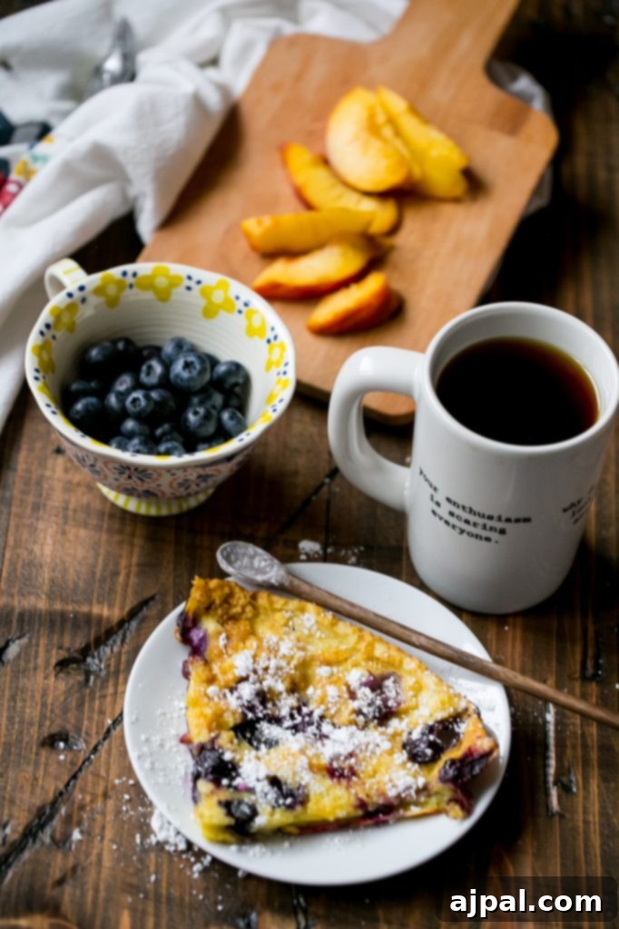 Close-up of a slice of Dutch baby pancake with peaches and blueberries
