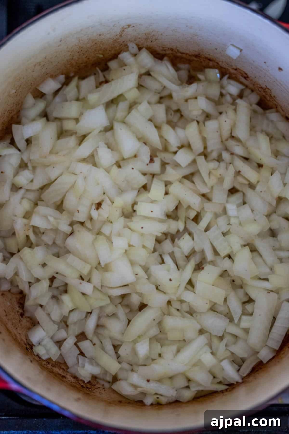Diced onions sizzle in a large pot, setting the foundation for a creamy hash brown hamburger soup.