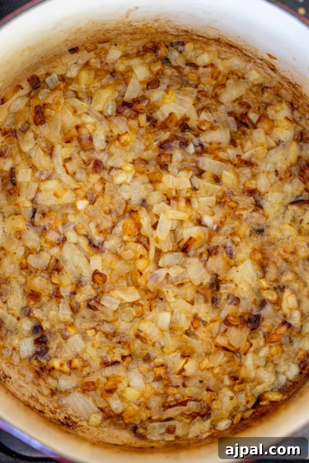Chopped onions caramelizing in a pot until golden brown set the savory foundation for a creamy hash brown hamburger soup.