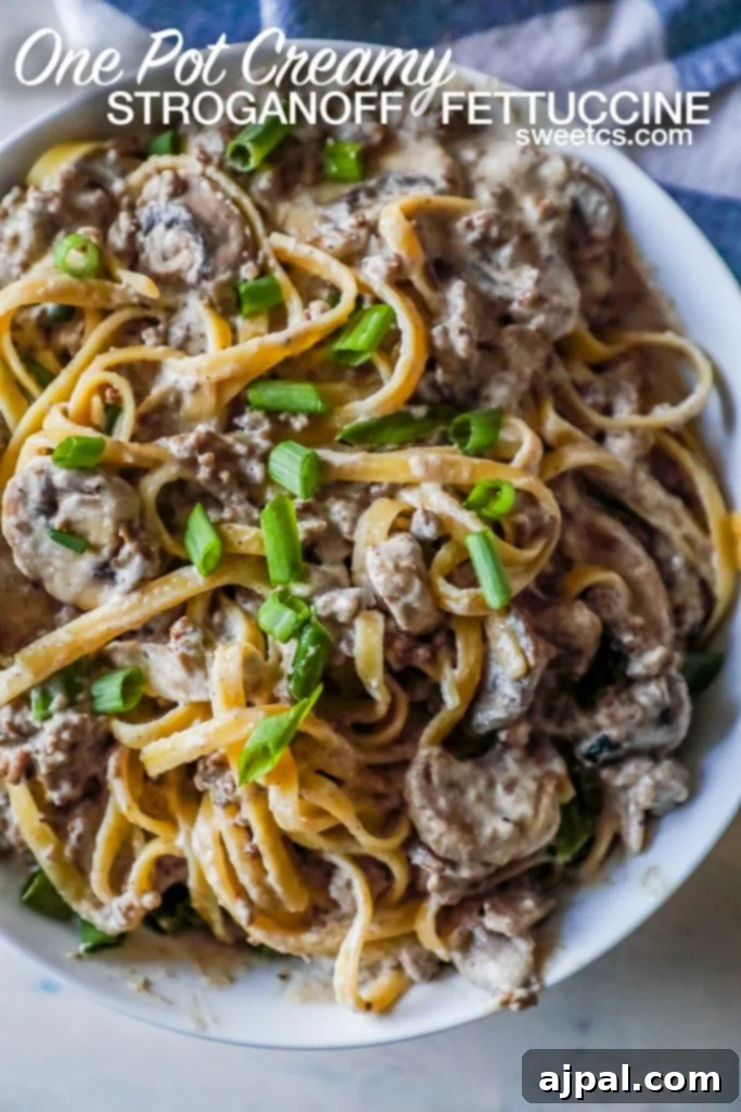 Noodles with creamy stroganoff with mushrooms and chives on top sitting on a white plate