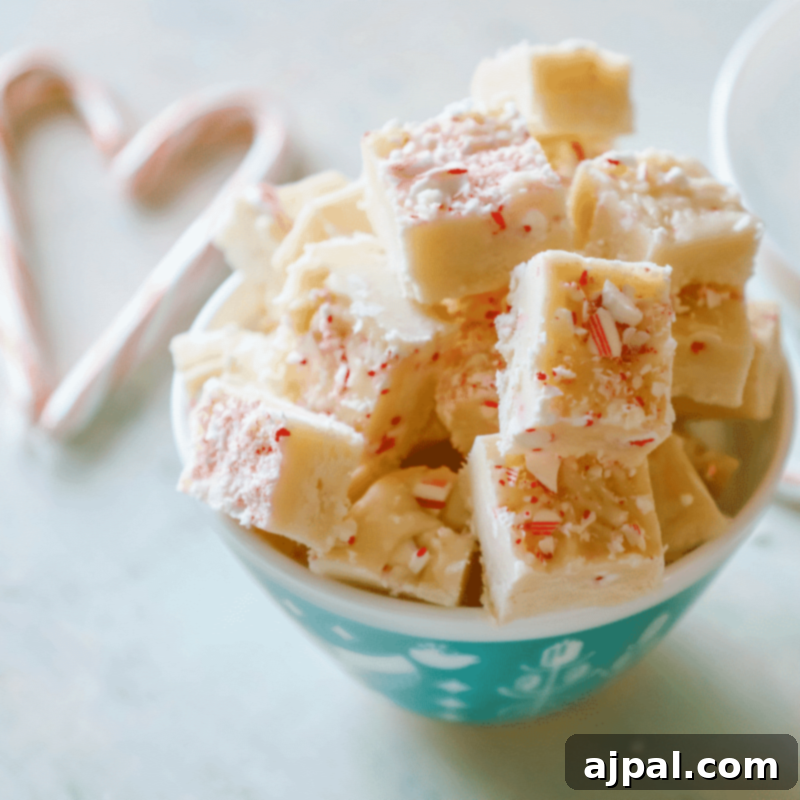 A bowl of festive Candy Cane Cake Batter Fudge, garnished with crushed candy canes and whole candy canes, inviting a taste of holiday magic.