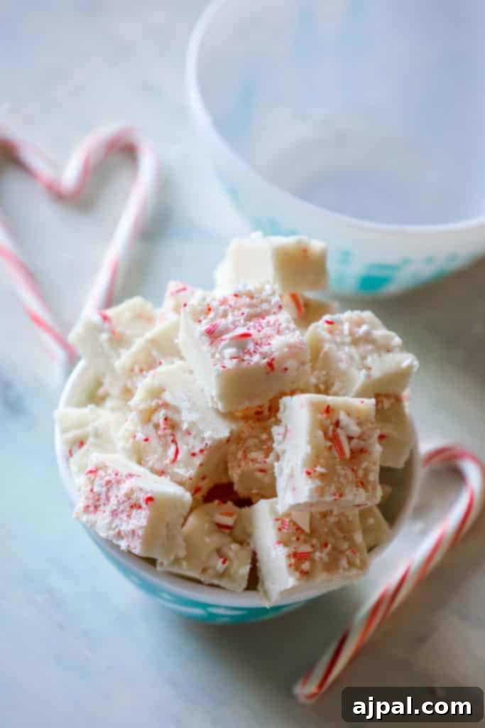 A tall, tempting slice of cake batter candy cane fudge, perfectly showcasing its vibrant colors and delicious texture.