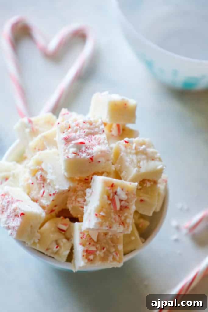 A close-up of festive candy cane cake batter fudge, sprinkled with crushed candy canes, signaling a delicious holiday treat.