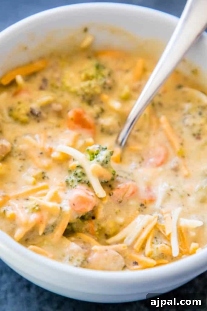 Hearty Slow Cooker Creamy Sausage and Broccoli Cheese Soup 6 A close-up of a rich and creamy broccoli cheese soup with savory sausage, served in a bowl with a spoon.