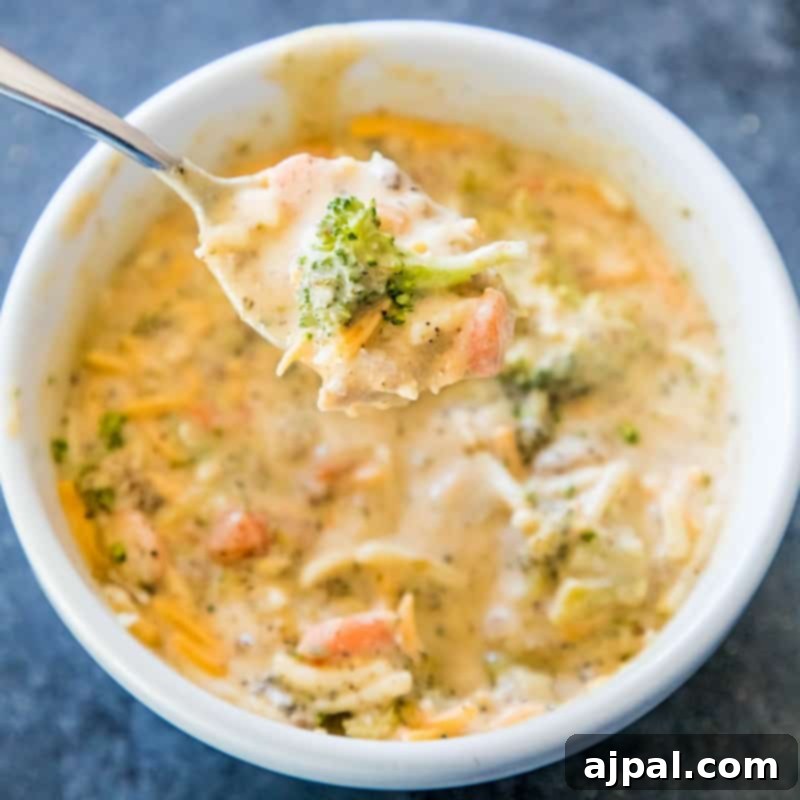Hearty Slow Cooker Creamy Sausage and Broccoli Cheese Soup 3 A close-up of a white bowl filled with creamy broccoli cheese soup, showing the rich texture and vibrant green broccoli florets.