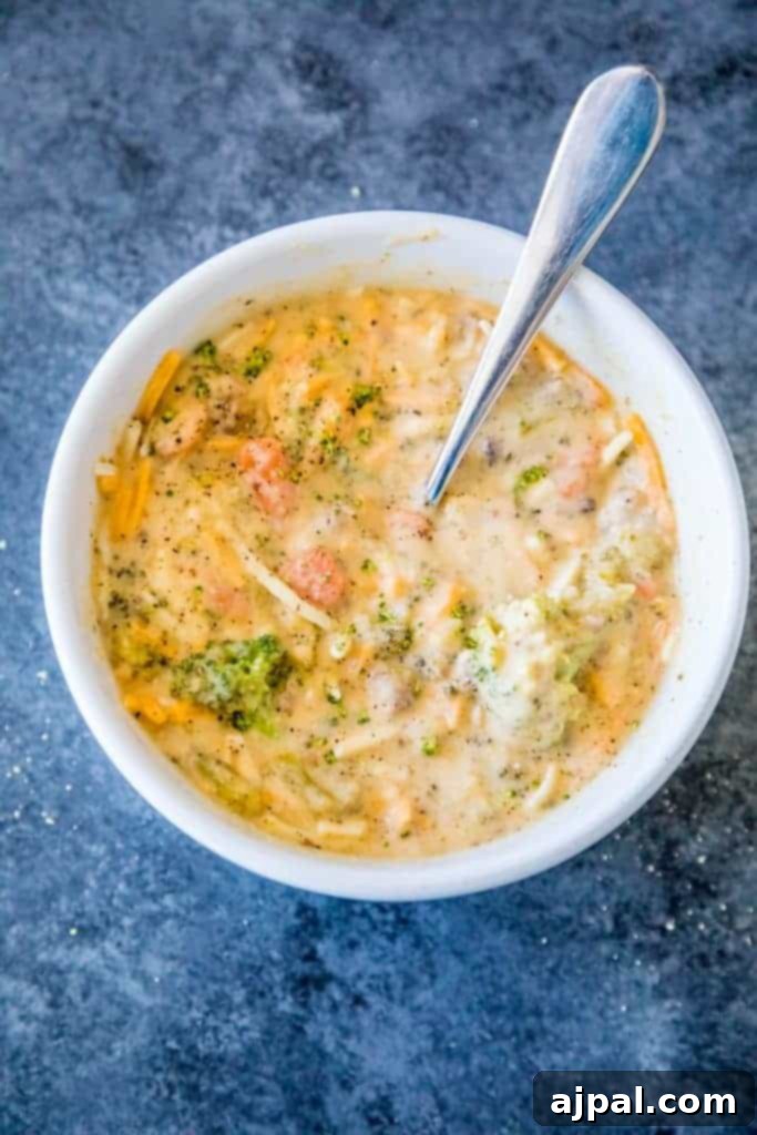 Hearty Slow Cooker Creamy Sausage and Broccoli Cheese Soup 5 A beautifully plated bowl of Slow Cooker Creamy Sausage and Broccoli Cheese Soup with a spoon, ready to be eaten.