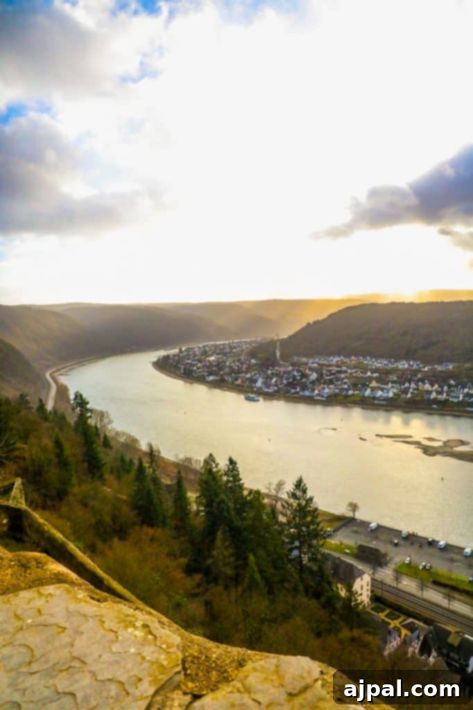 Marksburg Castle: Germany's Best-Preserved Medieval Gem 12 Panoramic view of the picturesque Rhine River as seen from the lush gardens atop Marksburg Castle, revealing the stunning valley landscape.