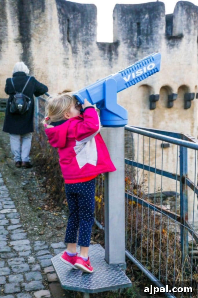 Marksburg Castle: Germany's Best-Preserved Medieval Gem 14 A curious little girl peers through a telescope at Marksburg Castle, enjoying a fun, interactive activity during her family visit to Germany.