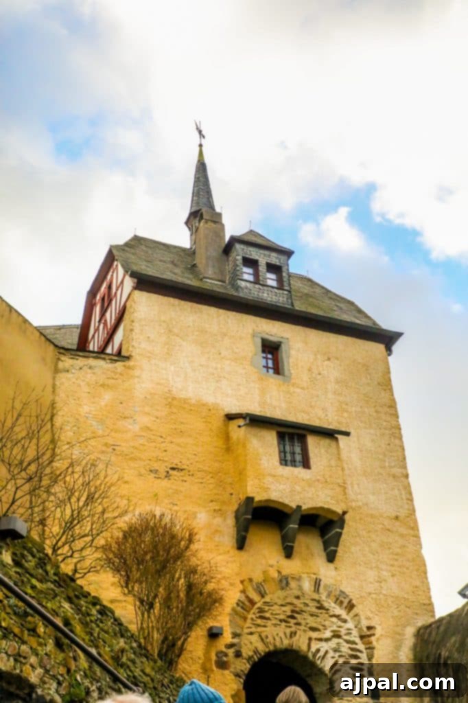 Marksburg Castle: Germany's Best-Preserved Medieval Gem 5 A diverse group of tourists stand in awe, admiring the formidable medieval architecture of Marksburg Castle, a premier historical site in Germany.