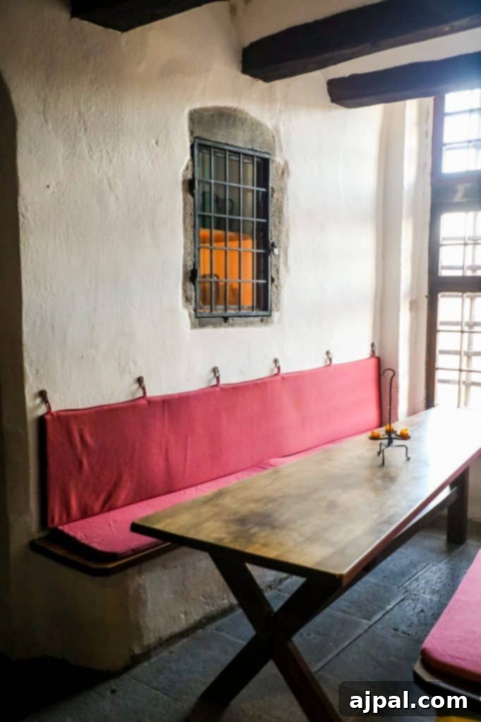 Marksburg Castle: Germany's Best-Preserved Medieval Gem 6 A cozy, small room within Marksburg Castle featuring a rustic wooden table and a bench adorned with inviting red cushions, hinting at medieval living.