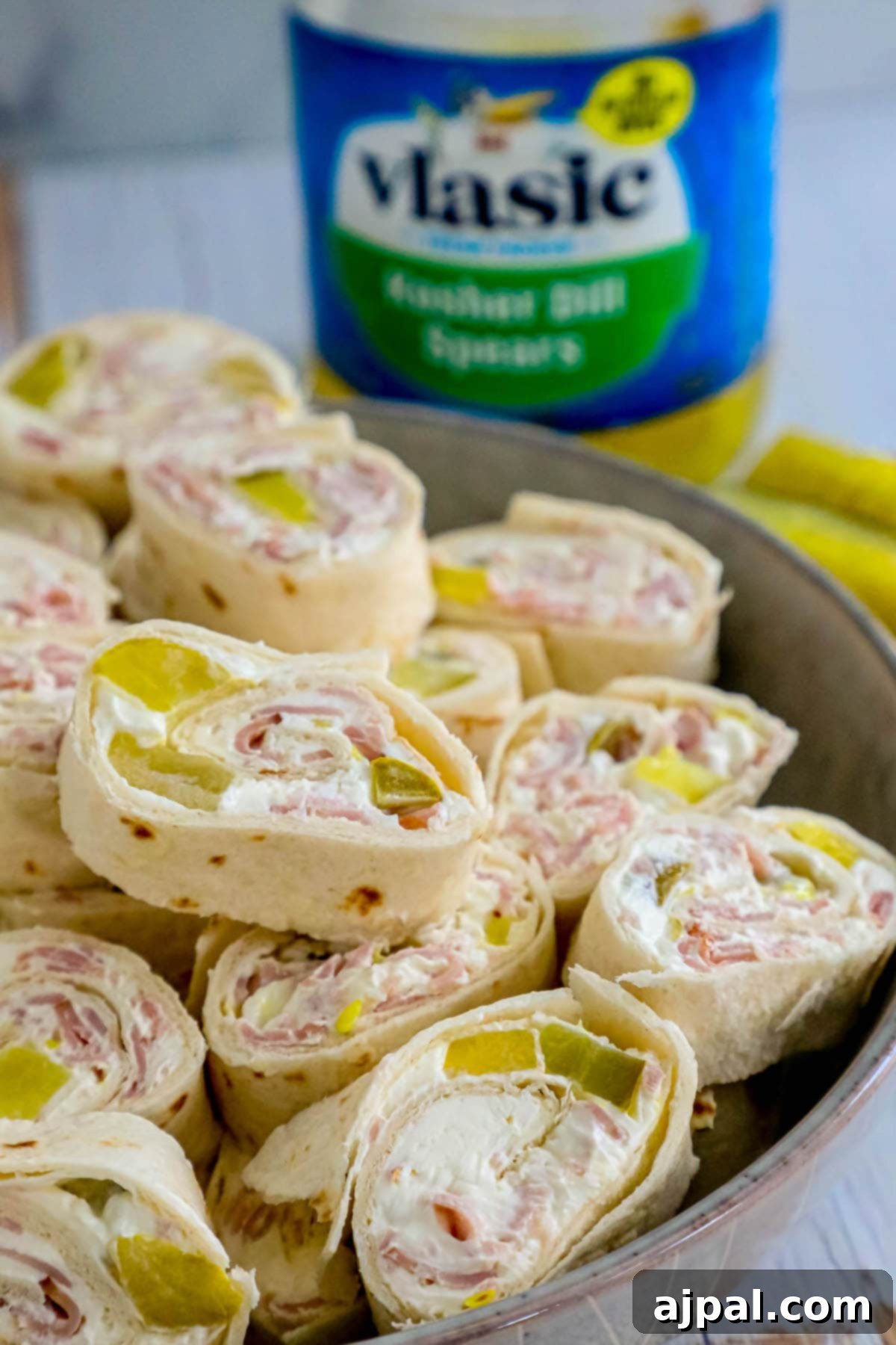 Game Day Feast: 12 Must-Try Dishes 4 A plate of neatly arranged dill pickle pinwheels, showing the layers of creamy filling, ham, and pickle wrapped in a tortilla, ready to serve as a party appetizer or light lunch.