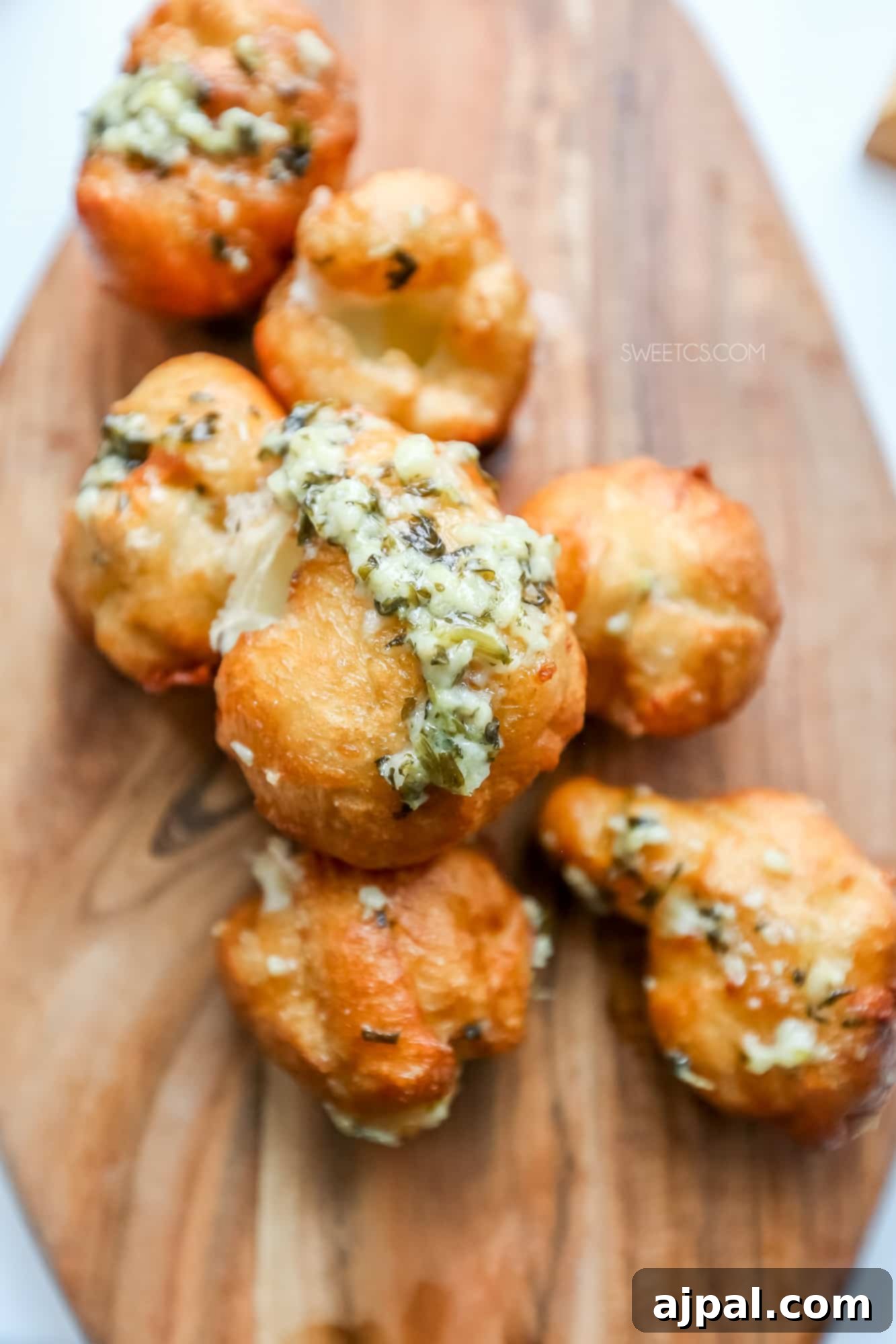 Game Day Feast: 12 Must-Try Dishes 6 Golden-fried garlic cheese bombs stacked on a wooden cutting board, with visible melted cheese oozing from the crispy crust, promising an epic appetizer.
