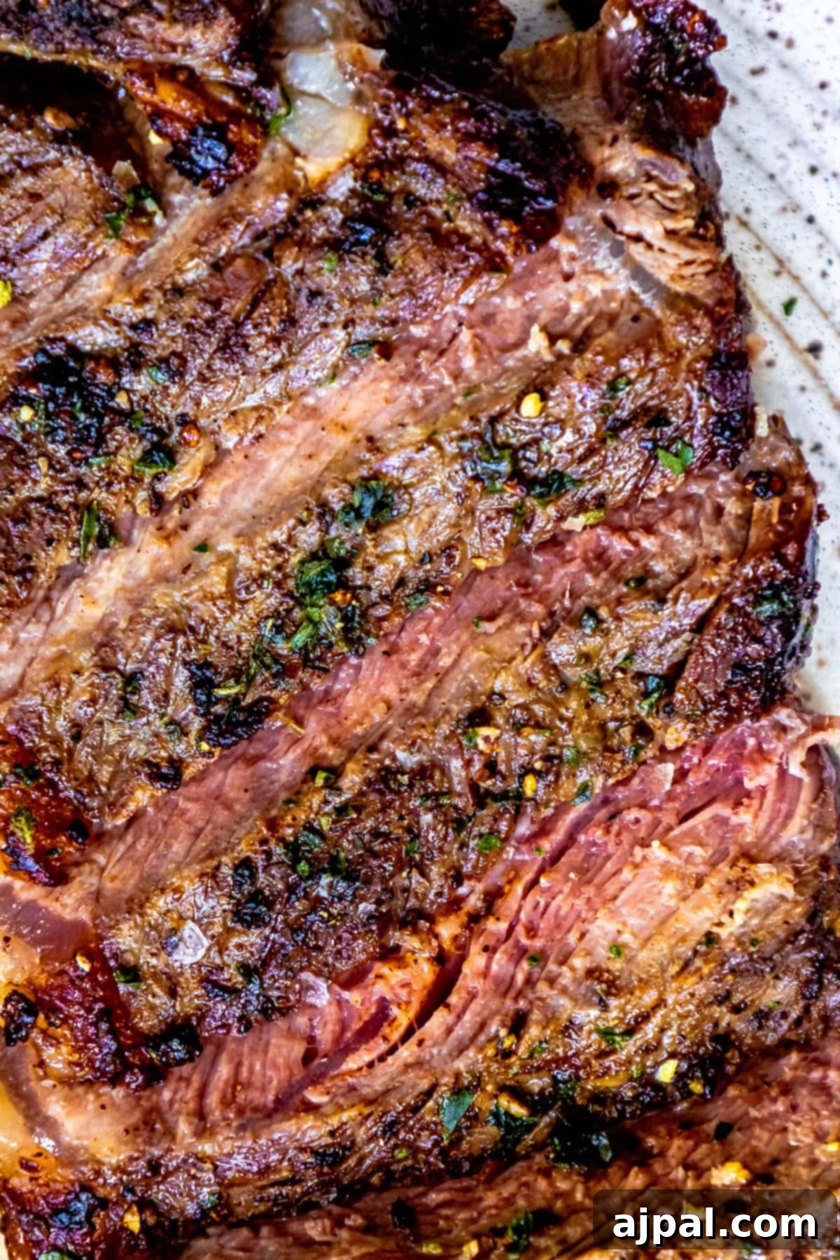Game Day Feast: 12 Must-Try Dishes 7 A perfectly cooked, juicy Ninja Grilled Steak resting on a plate, garnished with fresh herbs, showcasing its delicious char marks and tender interior.