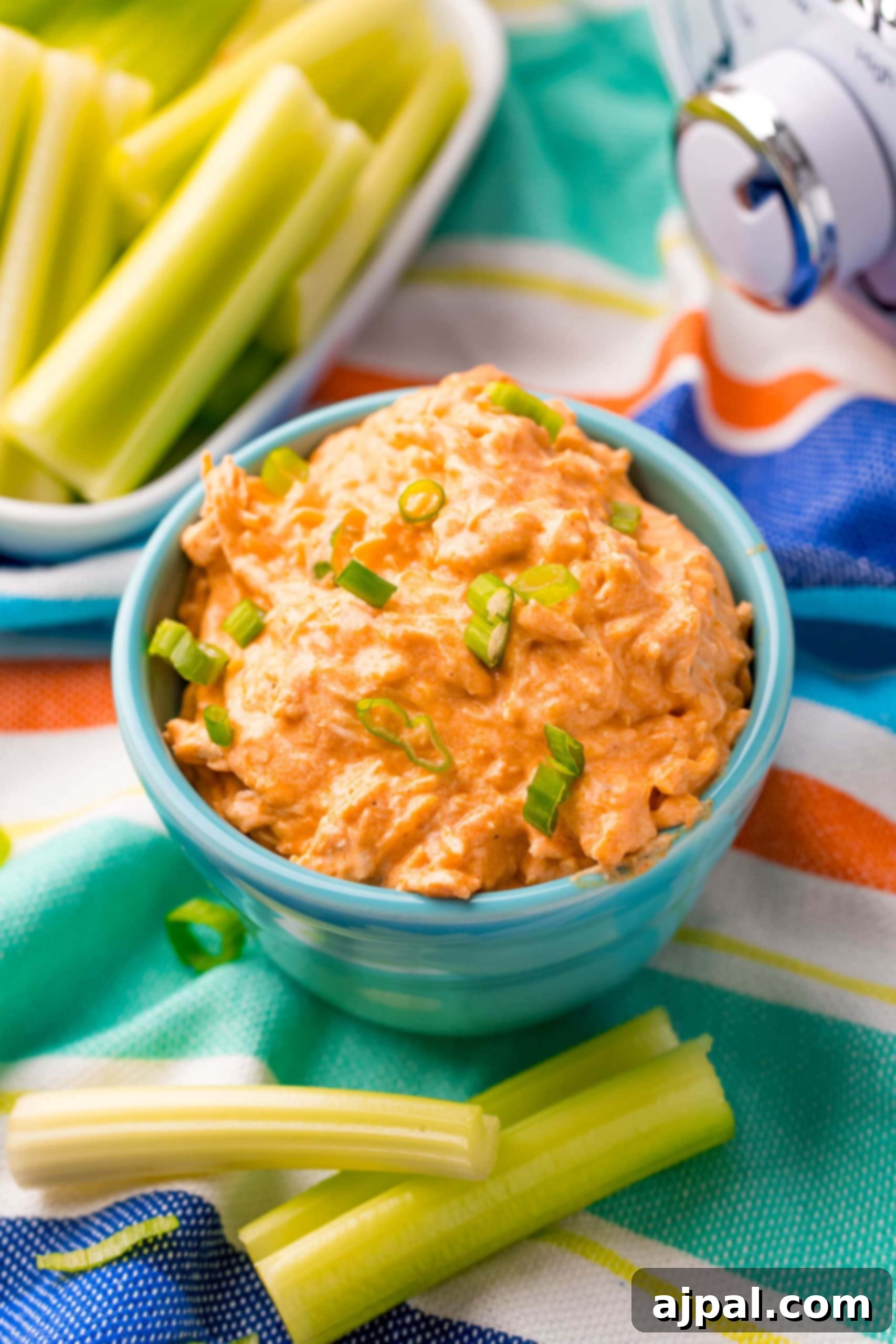 Game Day Feast: 12 Must-Try Dishes 9 A rich bowl of creamy buffalo ranch chicken dip, garnished with chopped green onions and served with crisp celery and carrot sticks for dipping, perfect for a keto-friendly game day.