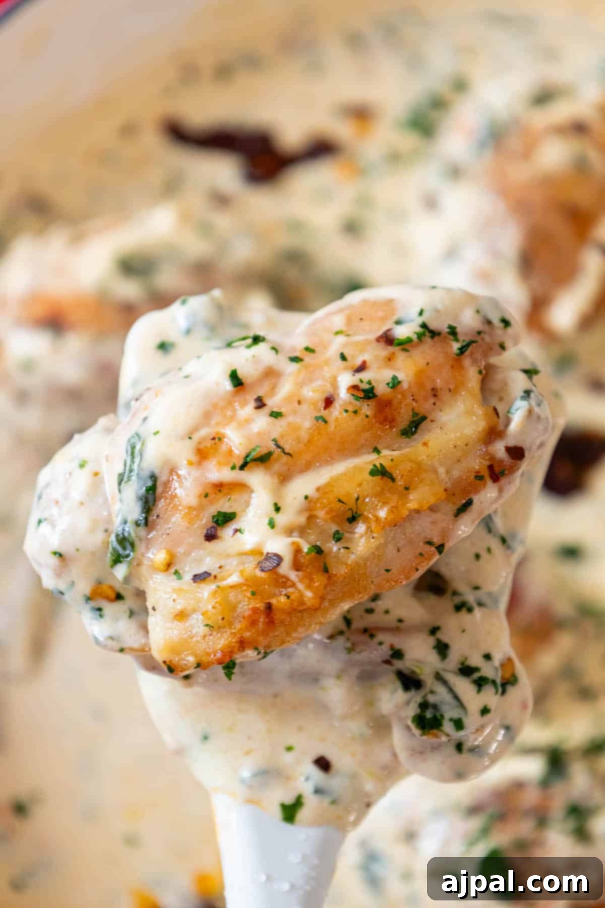 Decadent Creamy Tuscan Chicken Alfredo 2 A creamy spoonful of Tuscan chicken, showcasing its rich texture and vibrant ingredients.
