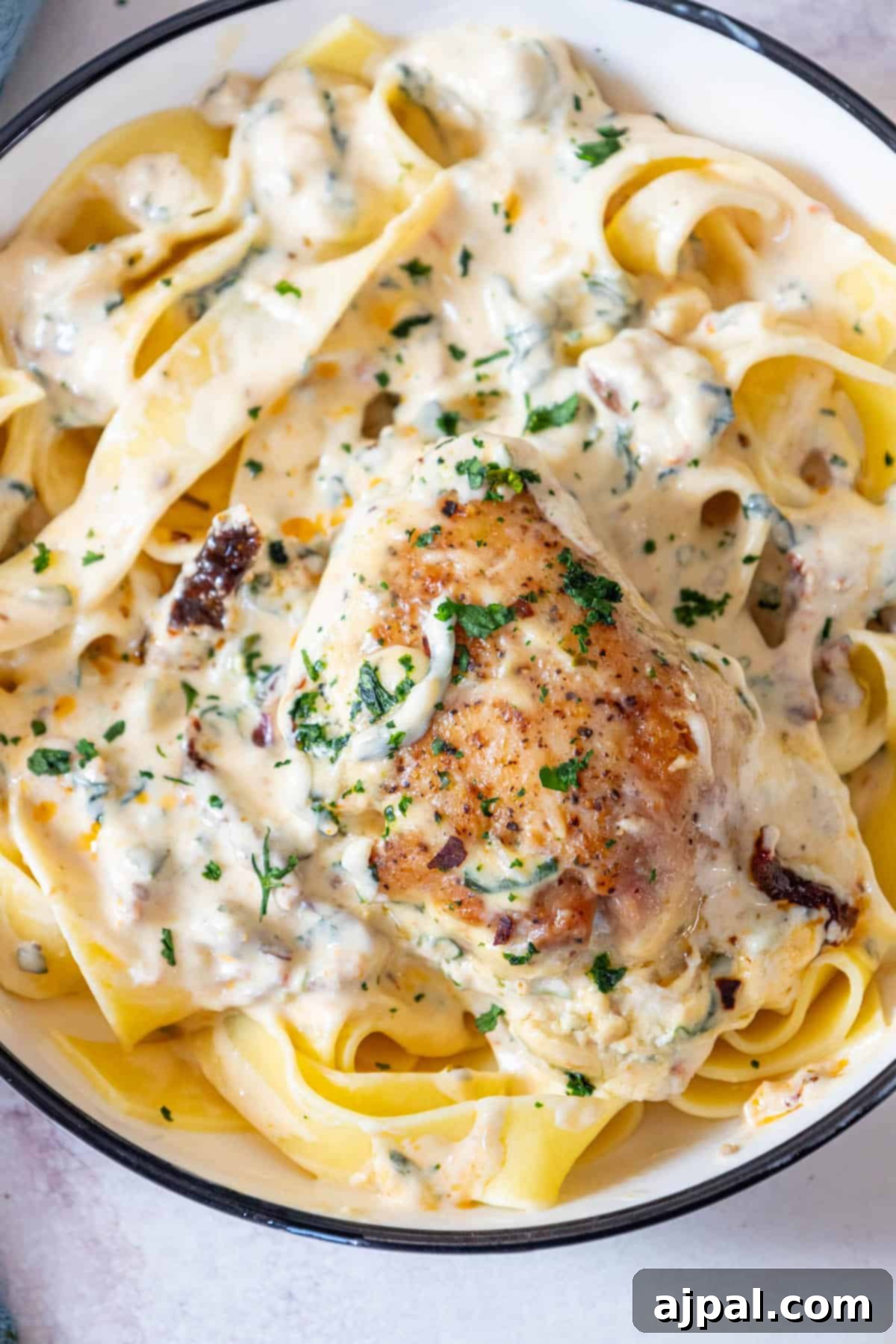 Decadent Creamy Tuscan Chicken Alfredo 4 A creamy bowl of Tuscan chicken pasta, garnished and ready to serve.