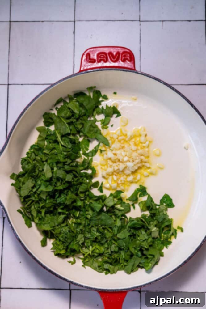 Decadent Creamy Tuscan Chicken Alfredo 5 A creamy tuscan alfredo chicken skillet with greens and corn on a tiled floor.