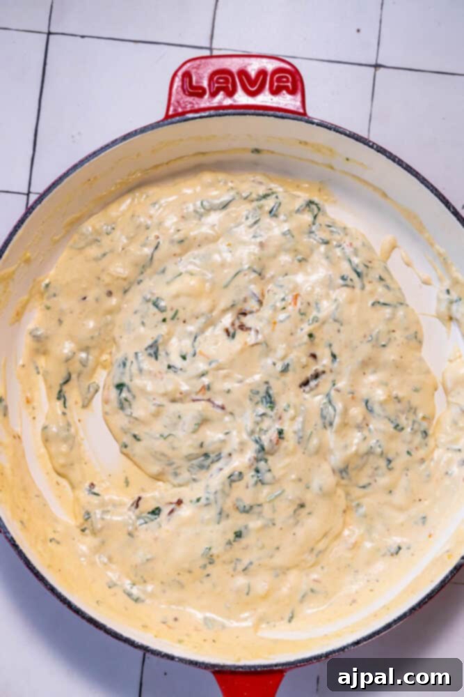 Decadent Creamy Tuscan Chicken Alfredo 7 A creamy skillet filled with spinach.