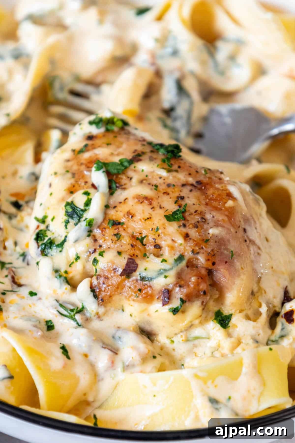 Decadent Creamy Tuscan Chicken Alfredo 10 A plate of creamy Tuscan chicken and pasta with a fork, ready to be enjoyed.