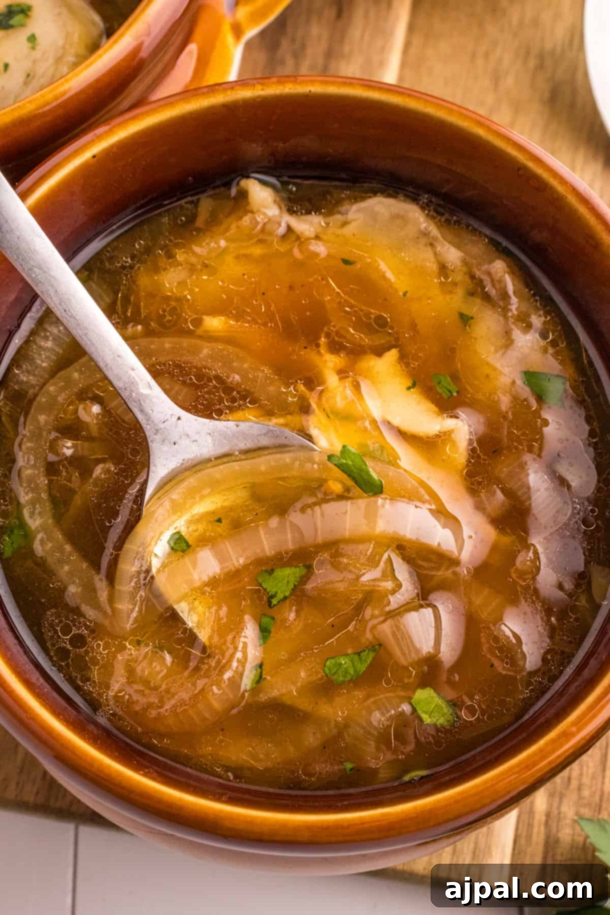 A delectable bowl of French Onion Soup, brimming with caramelized onions and crowned with a golden, cheese-laden crouton, ready to be enjoyed.