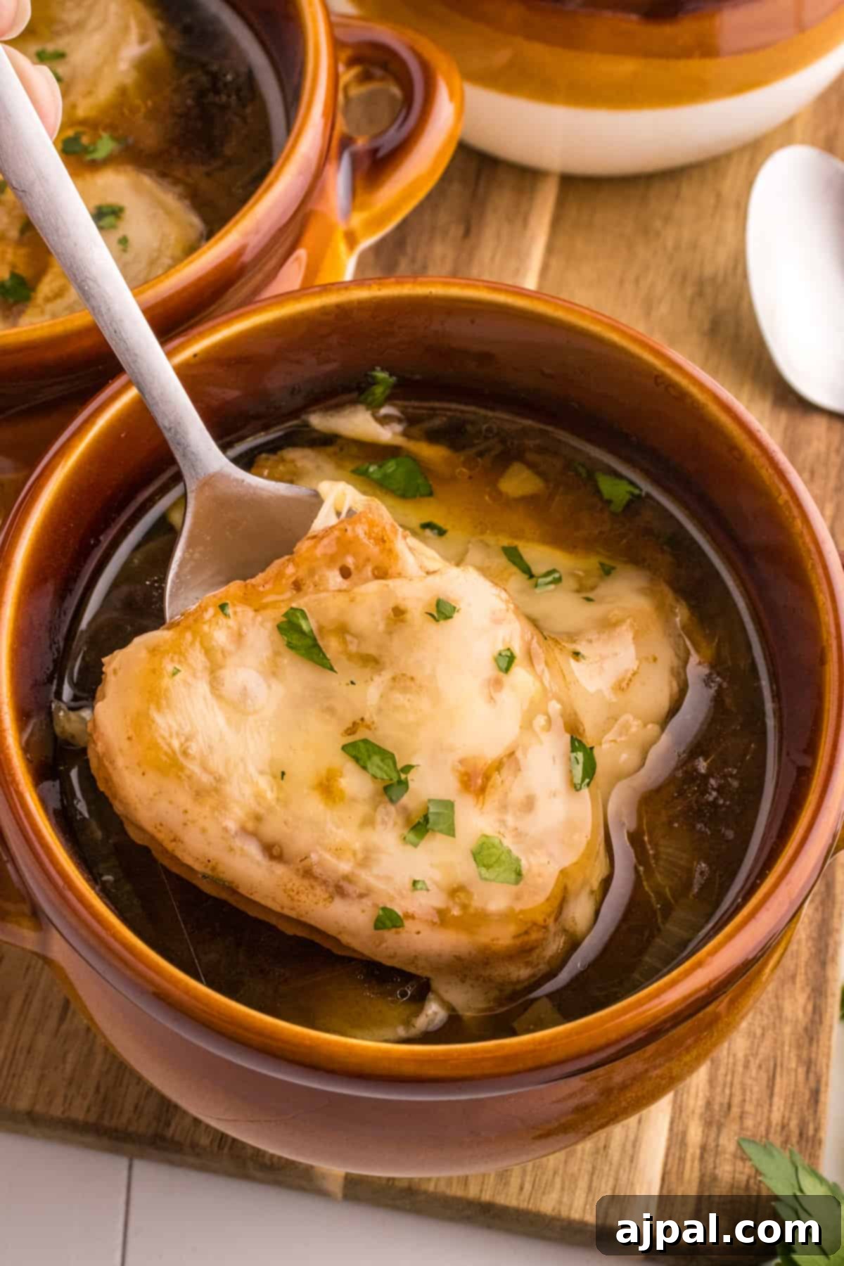 A inviting bowl of French onion soup, elegantly presented with a spoon, highlighting its comforting appeal.
