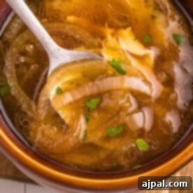 Easy French Onion Soup Recipe served in a bowl with onions and a spoon.