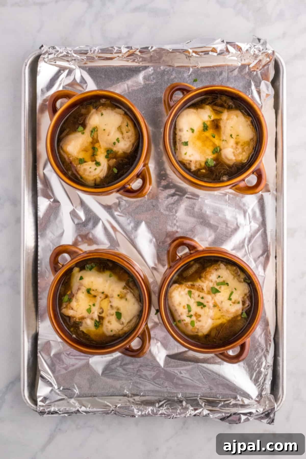A tempting tray of finished French Onion Soup, with richly browned, bubbling cheese over toasted bread, ready to be served.