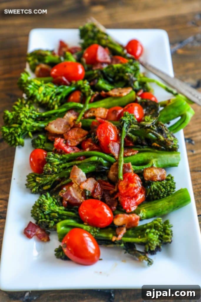 A visually appealing white plate showcasing a generous serving of charred broccolini, crispy bacon bits, and vibrant cherry tomatoes, ready to be enjoyed as a keto and paleo friendly side dish.