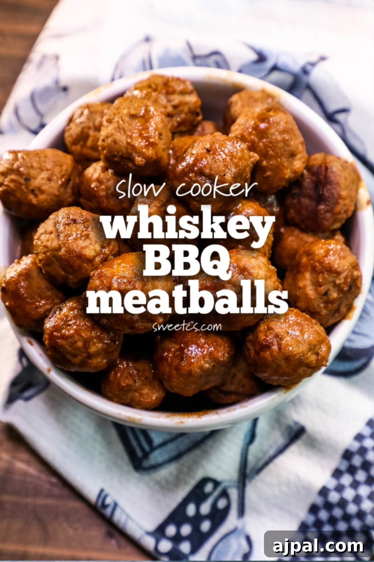 A bowl of savory BBQ meatballs, glazed with a rich whiskey sauce, with a blue and white patterned towel in the background, signaling a cozy, home-cooked meal.