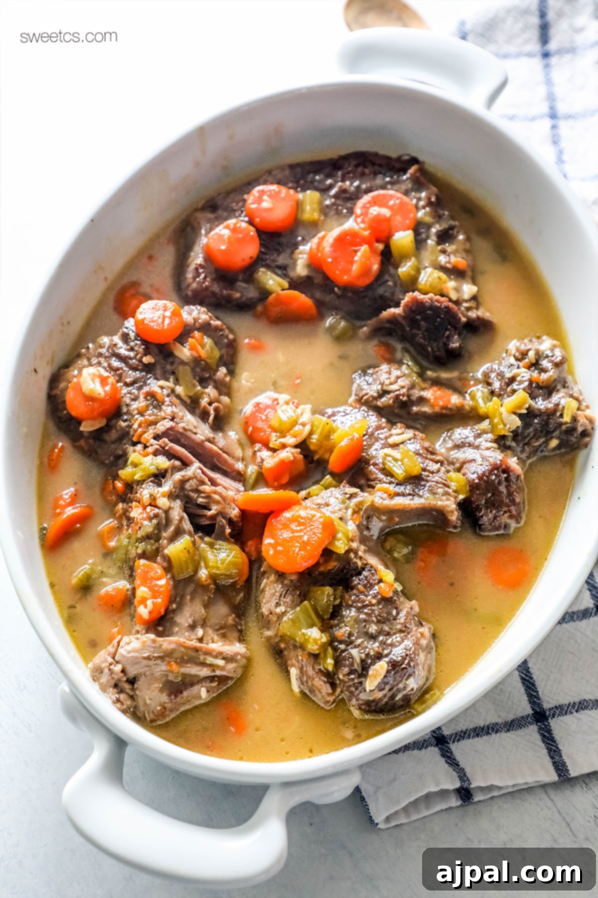 Hearty white casserole dish filled with a ranch pot roast, carrots, and a rich savory gravy.