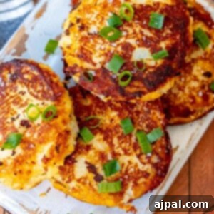 Crispy Irish potato pancakes garnished with fresh green onions on a rustic cutting board.