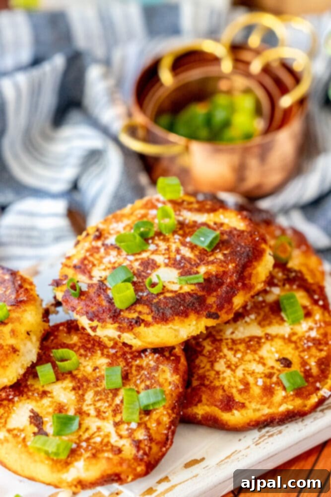 A close-up of freshly fried Irish potato pancakes on a white plate, topped with green onions.