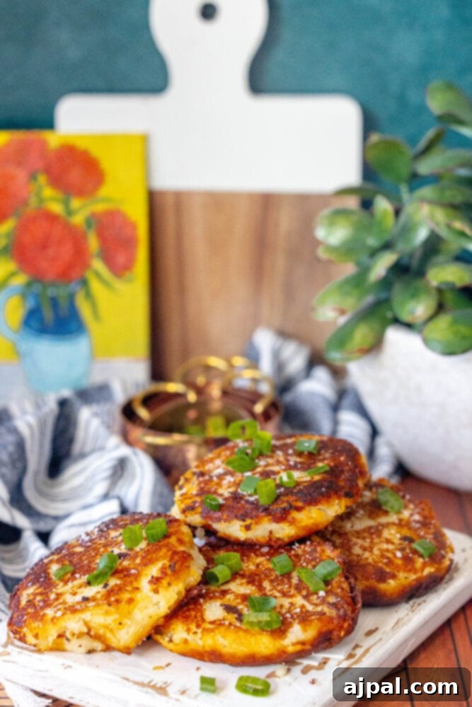 A stack of Irish potato pancakes with a generous topping of fresh green onions, served on a white plate.