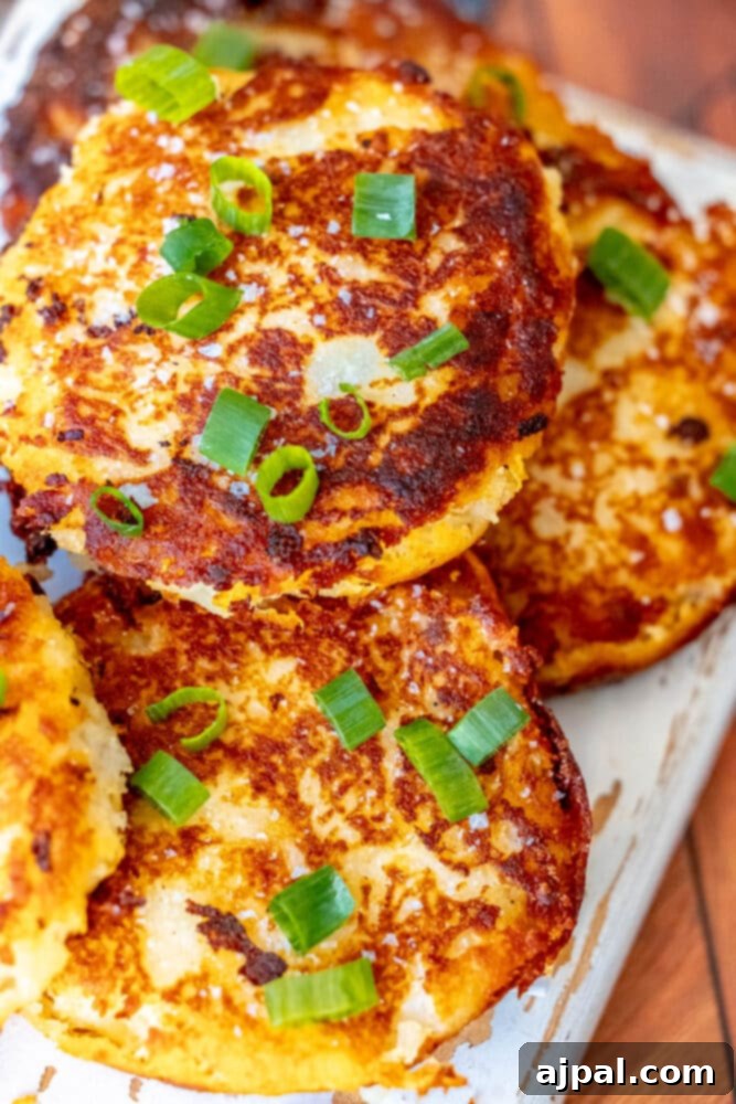 A beautifully stacked tower of Irish potato pancakes, topped with vibrant green onions, ready to be served.