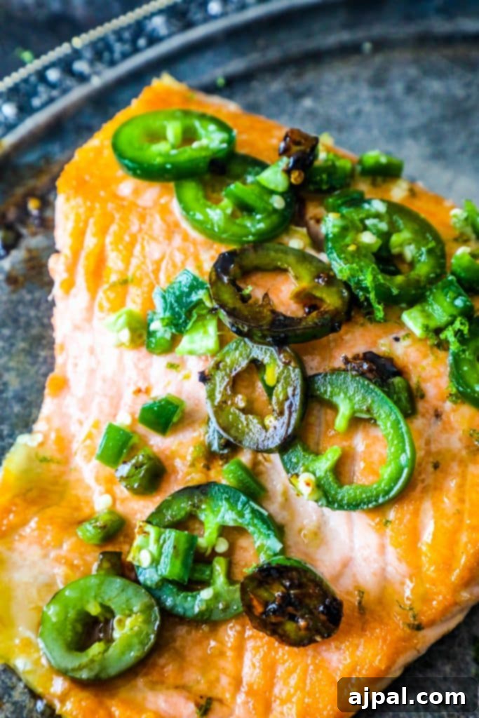 Honey Lime Glazed Jalapeno Salmon 3 Crispy-skinned salmon fillets coated in a zesty honey-lime-jalapeno glaze, garnished with fresh lime wedges on a silver platter.