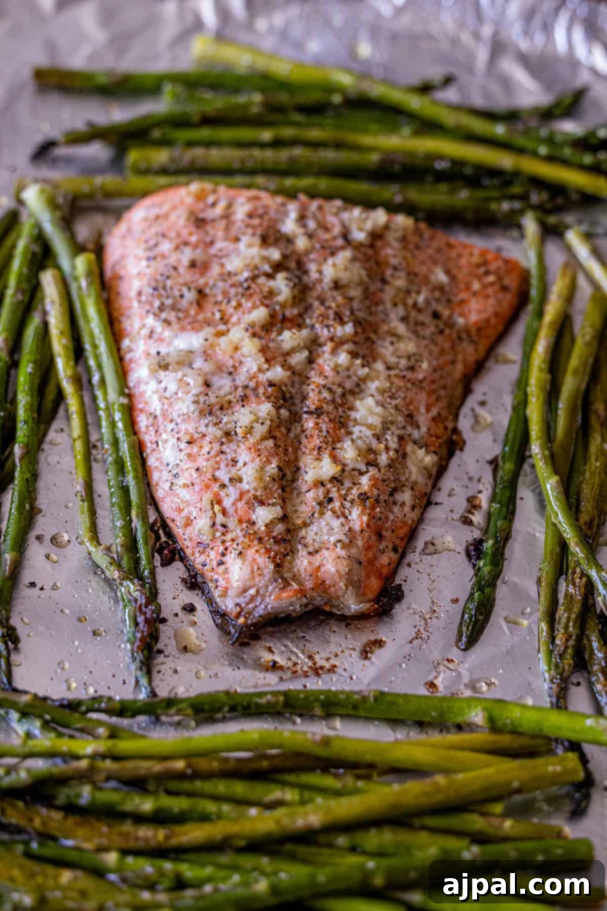 Zesty Sheet Pan Lemon Garlic Salmon and Asparagus 11 Baked salmon fillet seasoned with spices and garlic, surrounded by roasted asparagus spears on a foil-lined baking sheet—an easy salmon and asparagus recipe perfect for busy weeknights.