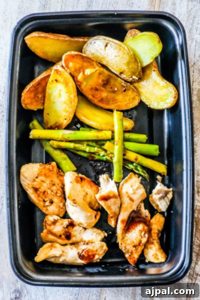 Prepared Instant Pot Balsamic Chicken and Vegetables meal prep bowl, ready to enjoy, with a fork on a black tray.