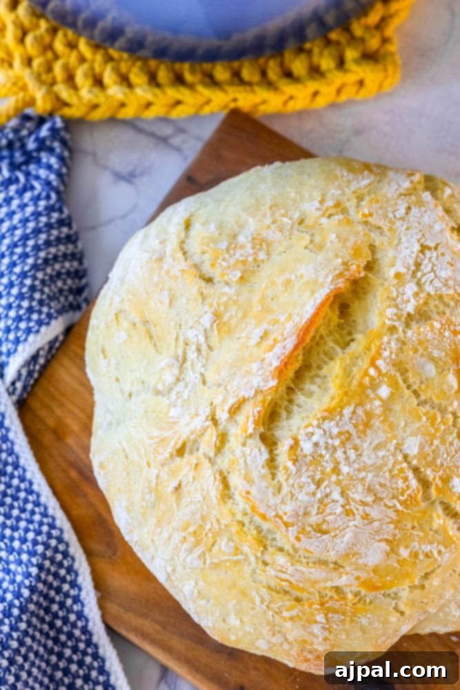 Effortless No-Knead Bread 2 A perfectly baked loaf of no-knead bread on a wooden cutting board, showcasing its golden-brown crust and inviting texture.